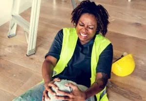 black female worker gripping hurt knee