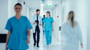 Two hospital staff members have a conversation while walking down the hallway.