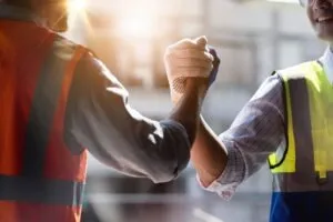 Two construction workers clasping hands. Seek fair damages for your losses with an Irvine construction accident lawyer. 