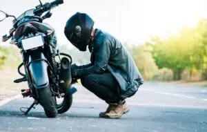 Motorcyclist repairing motorcycle on road in Diamond Bar