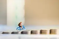 A bicycle toy rides up coins. What’s the average bicycle injury settlement in California?