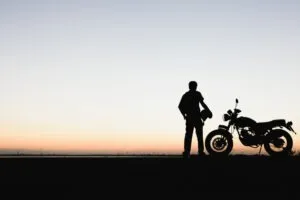Motorcycle rider holds helmet at sunset