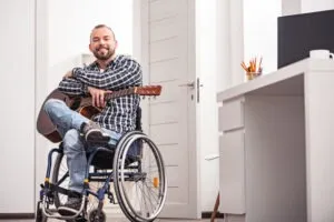 Motorcycle accident victim in a wheelchair holding a guitar. A motorcycle injury attorney in Oxnard can help to pursue the maximum compensatory damages.