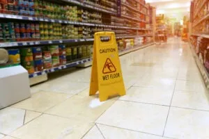 a grocery store aisle with a yellow wet floor sign