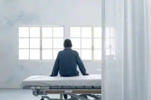 a male patient sitting on a bed in a psych ward