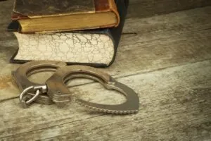 Concept of handcuffs and law books representing a bench warrant. Learn how to clear a bench warrant without going to jail by speaking with us.