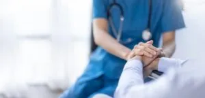 Female nurse holds her senior patient's hand. Call an Orange personal injury lawyer today.