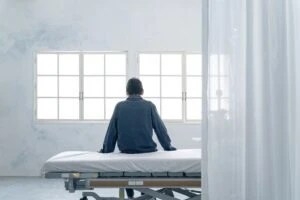 A psychiatric patient on a 72-hour hold sits on a bed and considers the consequences of a 5150.