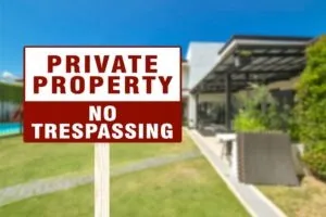 A house with a No Trespassing sign on a stake. A lawyer can tell you more about California Penal Code Section 602.5: Aggravated Trespass.