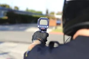 An officer uses a radar gun to catch people violating California Vehicle Code Section 22349: Speeding Over 65 MPH.