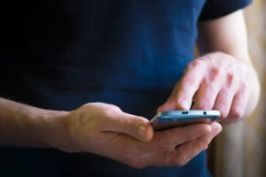 A man holding a cell phone, reading a text message. Discover how to tell if a cop is texting you.