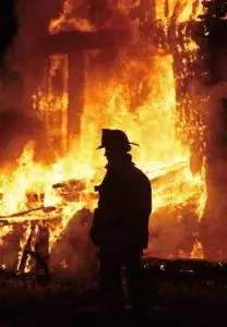 A firefighter stands in front of a building fire