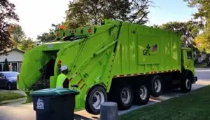 A garbage truck lifts a dumpster.