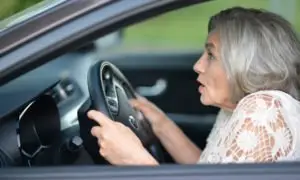 An older driver sits in the driver’s seat of her car