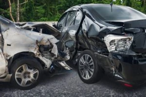 A black car has been hit in the side by a gray car.