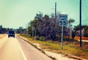 A car driving on a Florida road near a speed limit sign.