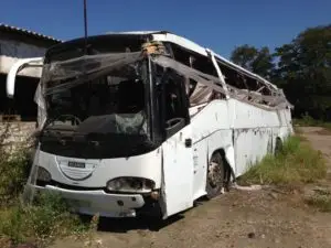 A damaged bus on the side of a road.