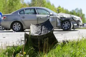 A damaged car part in front of a damaged car