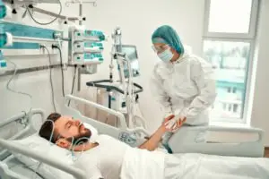 A doctor checking on a man in a hospital bed.