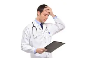 A doctor holds his head while looking at a chart