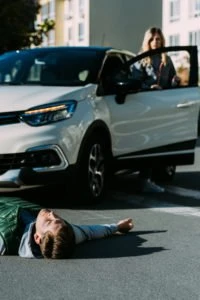 A driver checks on an injured pedestrian after a collision.