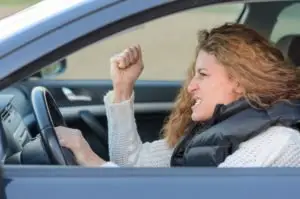 A driver shakes her fist angrily.