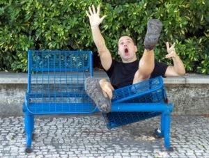 A man falling backward on a broken bench.