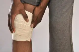 A man holds his bandaged knee.