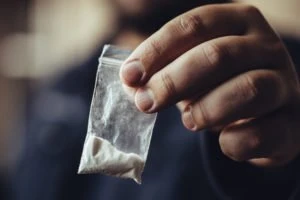 A man holds a small bag of drugs