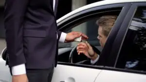 A man in a suit hands off drugs to a driver