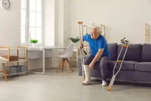 A man with an injured leg and crutches sits on a couch.
