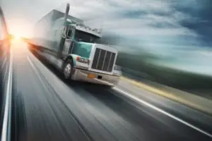 A semi-truck speeding on a freeway.