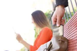 A thief taking a phone from a woman’s purse.