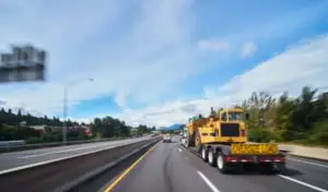 A truck with an oversized load drives on a highway.