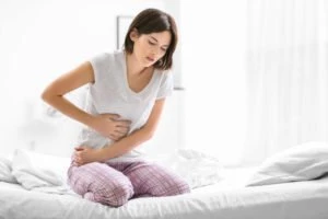 A woman holds her abdomen in pain