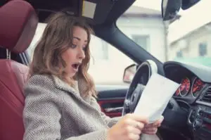 A young woman looking shocked at a traffic ticket.