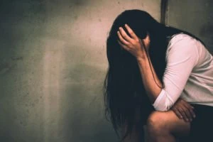 A young woman sitting alone, crying.