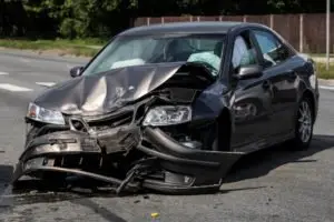 A black car with front-end damage from head-on-collision