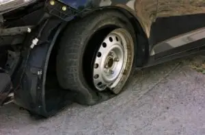 A blown-out tire on a damaged car after an accident.