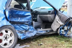 A blue car with a damaged passenger side.