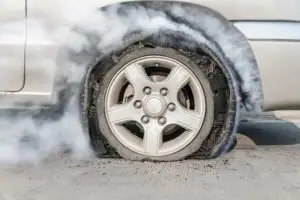 A burst tire with smoke surrounding it.