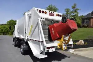 A garbage truck stopped on a road.