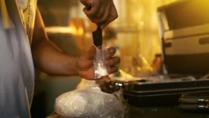 A man fills a small bag with drugs.