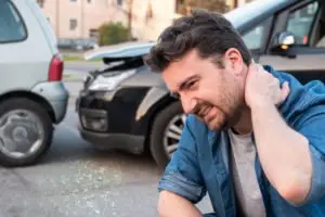 A man gripping his neck after a car accident.