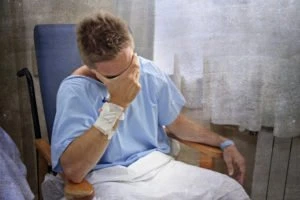 A man in a hospital gown crying.