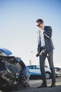 A man looks shocked looking at car damage.
