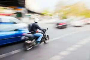 A motorcyclist speeding near cars on a highway.
