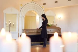 A mourning woman standing over a casket.