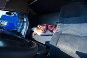 A truck driver sleeping in his cab.