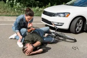 A woman checking on an injured bicyclist.